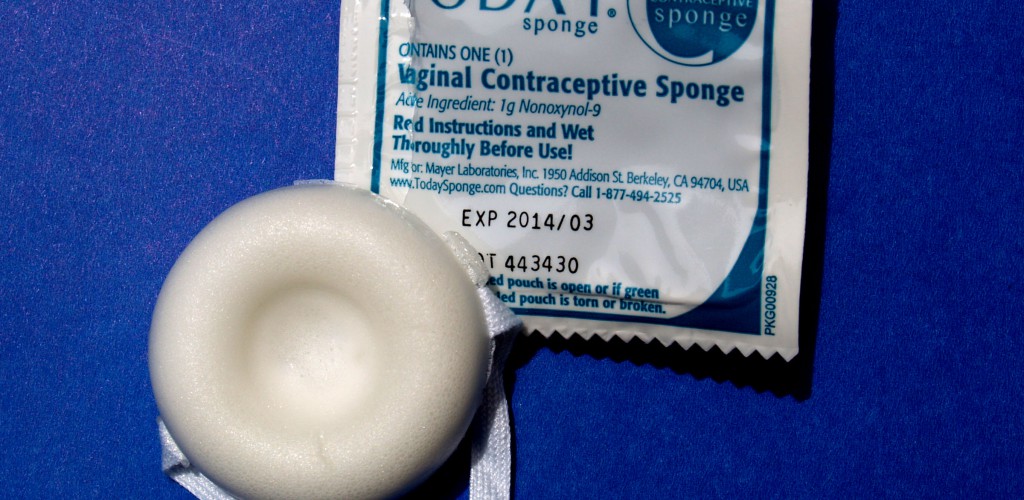 A photo of a vaginal contraceptive sponge and its opened wrapper. They are on a blue background.