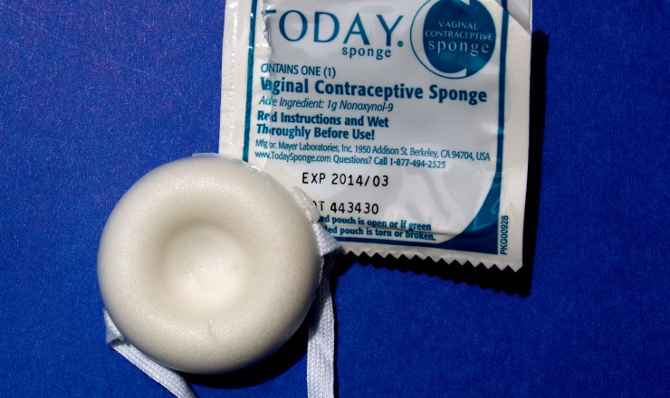 A photo of a vaginal contraceptive sponge and its opened wrapper. They are on a blue background.